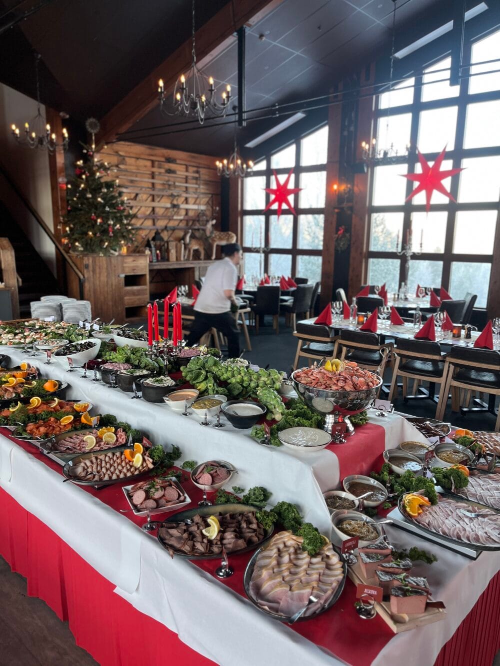Julbord uppdukat i restaurang, kalla rätter och dekorationer, julgran och dukade bord.