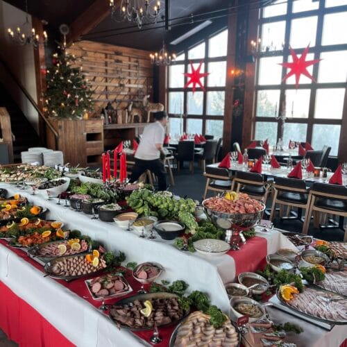 Julbord uppdukat i restaurang, kalla rätter och dekorationer, julgran och dukade bord.