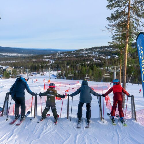Person står med färgglada skidor i puckelpist under klar himmel i soligt skidområde