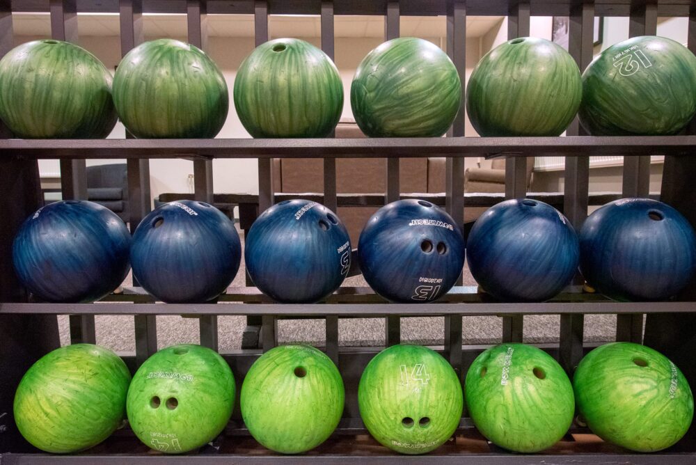 Bowlingklot i olika färger uppradade på ställ i bowlinghall