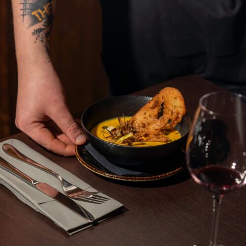 Svampesuppe i en sort skål med en skive ristet brød, serveret på et mørkt bord.