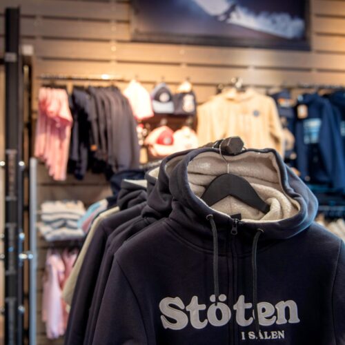 Stand with dark hoodie saying “Stöten i Sälen” in store, surrounded by sweatshirts and caps
