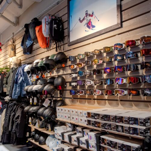 Wall of ski goggles in different colours, helmets and winter clothing in ski equipment shop