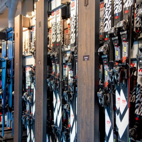 Rows of alpine skis in different sizes and colours are arranged in the ski rental shelving system