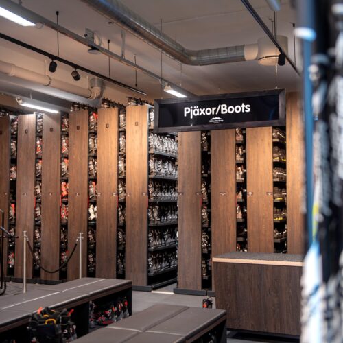 Skileje med hylder fulde af skistøvler og et skilt med teksten “Skistøvler”, moderne indretning