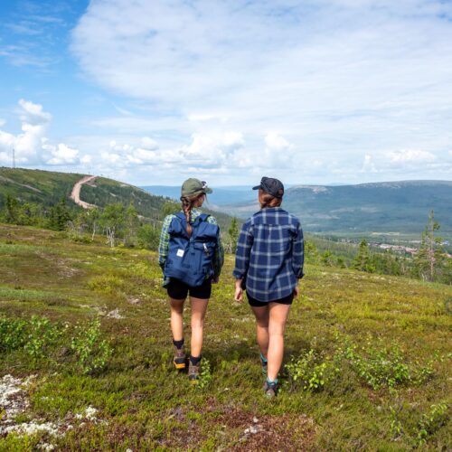 Two people walking on mountain heath overlooking green valleys and blue sky