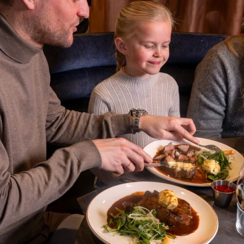 Table set with plates of meat, potatoes, gravy and salad and a bowl of chips.