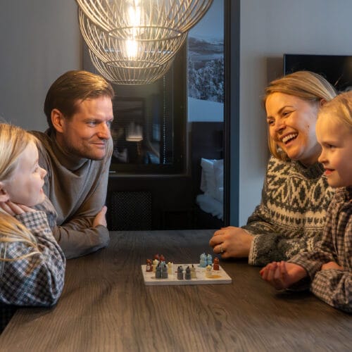 Föräldrar och barn spelar spel vid matbordet.