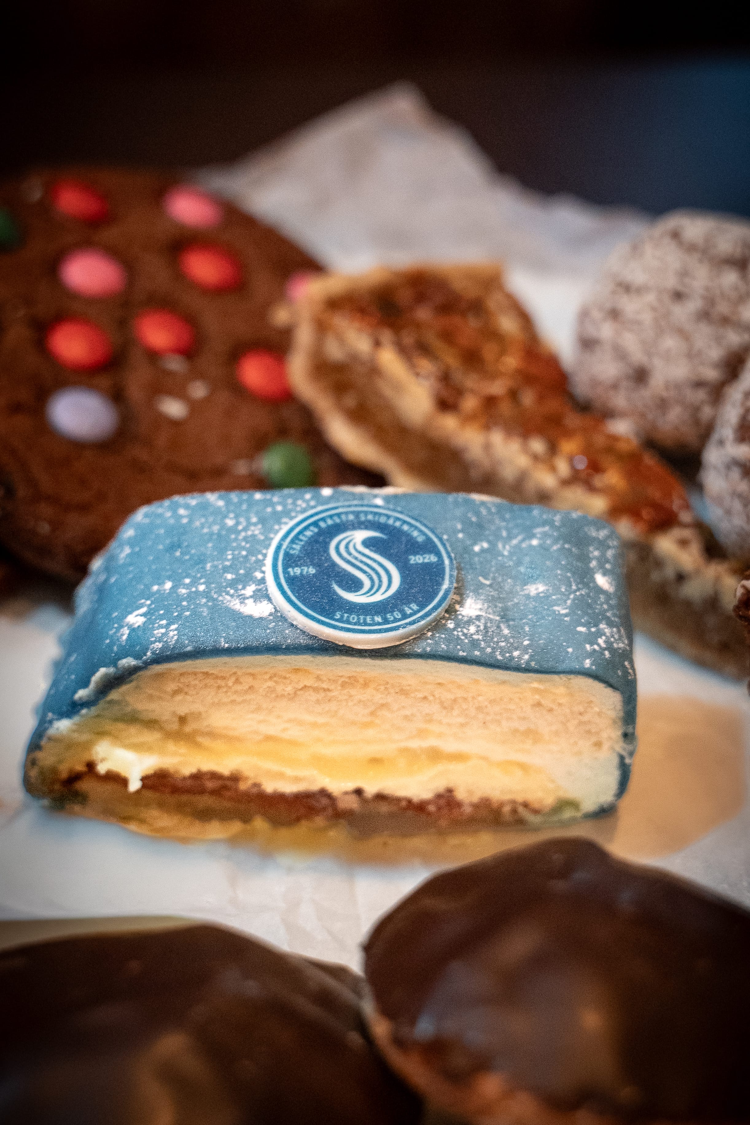 Blå prinsessbakelse med stöten 50års logga på, omringad av flera andra olika bakverk.