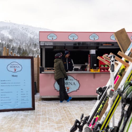 Outdoor restaurant at the ski slope where a person orders food at a pink kiosk.