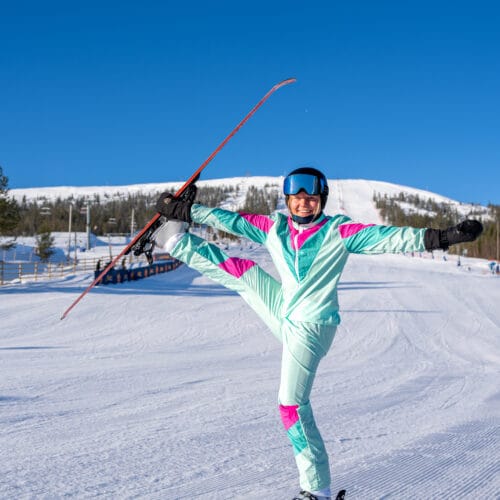 People in colourful clothes on a ski slope performing ski ballet.