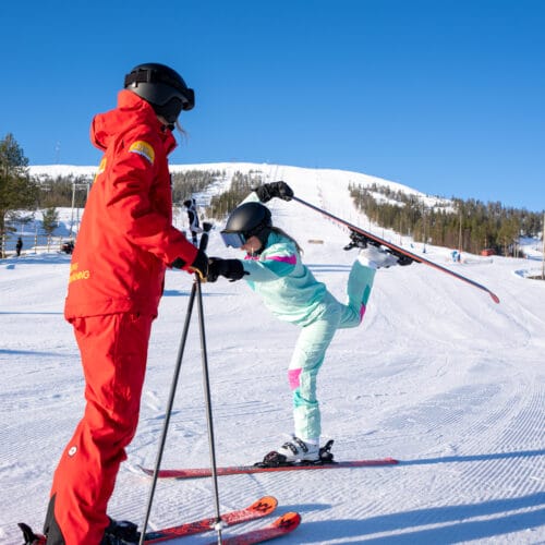 People in colourful clothes on a ski slope performing ski ballet.